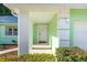 Inviting covered entryway with white door, green walls, and well-manicured landscaping at 3834 Se 9Th Pl, Ocala, FL 34471
