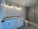 This bathroom features a double sink granite countertop, modern lighting, and tiled walk-in shower at 4424 Sw Carnation Ct, Dunnellon, FL 34431