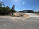 A single-story home with a gray exterior, concrete driveway, a front yard covered with sand, and a blue sky at 4424 Sw Carnation Ct, Dunnellon, FL 34431