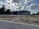 Unfinished single-story home with gray siding, a front yard covered with sand, and a cloudy sky at 4424 Sw Carnation Ct, Dunnellon, FL 34431
