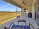 Covered screened patio with ceiling fan, seating, grill, and expansive field view at 5198 Ne 19Th Pl, Ocala, FL 34470