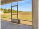 Covered screened patio overlooking a large grassy field with trees in the distance at 5198 Ne 19Th Pl, Ocala, FL 34470