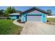 Inviting single-story home with an attached garage, vibrant blue exterior, and manicured landscaping at 5220 Sw 161St Place Rd, Ocala, FL 34473