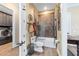 Bathroom featuring a shower over tub with glass enclosure, adjacent to laundry room with modern appliances at 5484 Sw 30Th Ave, Ocala, FL 34471