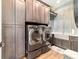 Modern laundry room boasts gray cabinets, stainless steel washer and dryer, and utility sink at 5484 Sw 30Th Ave, Ocala, FL 34471