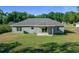 Back exterior view of home with a covered patio overlooking the green backyard at 5899 Pecan Rd, Ocala, FL 34472