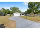 Single-story home with a gray driveway leading to an attached garage, nestled in a serene neighborhood at 614 Third Ave, Lady Lake, FL 32159