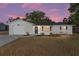 Charming single-story home with an attached garage, a dark front door and neat landscaping, set against a colorful sky at 614 Third Ave, Lady Lake, FL 32159