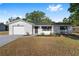 Charming single-story home with a white exterior, attached garage, and well-maintained front yard at 614 Third Ave, Lady Lake, FL 32159