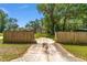 Long driveway leading to a fenced property with mature trees, a home, and a storage shed at 6318 Nw 52Nd Ave, Ocala, FL 34482