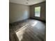 A bright bedroom features wood-look floors, a large window, and access to other rooms in a light, neutral color palette at 6658 Sw 165Th Ct, Ocala, FL 34481
