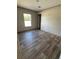 A bright bedroom features wood-look floors, a large window, and access to other rooms in a light, neutral color palette at 6658 Sw 165Th Ct, Ocala, FL 34481