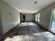 A bright living room features wood-look floors, a large window, and access to other rooms in a light, neutral color palette at 6658 Sw 165Th Ct, Ocala, FL 34481