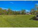 Large backyard showcasing a vast green space with minimal landscaping and a covered patio area at 716 Hickory Course Loop, Ocala, FL 34472