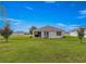 Well-kept backyard with a covered patio, green lawn, and distant views of neighboring homes at 716 Hickory Course Loop, Ocala, FL 34472