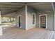 A covered porch featuring a wooden deck, offering a view of the surrounding neighborhood and side entrance at 721 Ne 2Nd St, Ocala, FL 34470