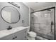 Modern bathroom featuring gray vanity, round mirror, toilet, and glass-enclosed tiled shower at 7585 Sw 79Th Pl, Ocala, FL 34476