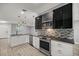 Well-designed kitchen with stainless steel appliances, stone backsplash, pendant lights, and black counter tops at 7585 Sw 79Th Pl, Ocala, FL 34476