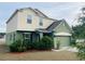 Two-story home featuring green and beige tones, a two-car garage and mature landscaping at 807 Glen Creek Ct, Fruitland Park, FL 34731