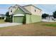 A view of the green two car garage, green siding, and well maintained lawn and landscaping at 807 Glen Creek Ct, Fruitland Park, FL 34731