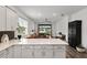 Open kitchen view showcasing white cabinets, stainless steel appliances and an adjacent living area at 8798 Sw 79Th Pl, Ocala, FL 34481