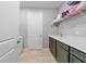 Spacious laundry room with tile floors, gray cabinets and countertops, and storage shelves above the sink at 8875 Sw 58Th Street Rd, Ocala, FL 34481