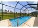 Screened pool features a small waterfall feature and tranquil views of the fenced backyard with green grass at 8875 Sw 58Th Street Rd, Ocala, FL 34481