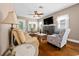 Comfortable living room features hardwood floors, a ceiling fan, and a stone fireplace with a mounted TV at 942 Ne 5Th St, Ocala, FL 34470