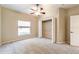 A well-lit bedroom has a ceiling fan, neutral carpet, closet with a shelf and rod, and window at 9525 Sw 53Rd Cir, Ocala, FL 34476