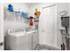 Bright laundry room includes a washer and dryer, shelving, storage rack, and utility sink at 10589 Sw 98Th Ln, Ocala, FL 34481