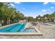 Long lap pool with clear blue water, a separate hot tub, surrounded by lush greenery, patio seating, and palm trees at 10833 Sw 86Th Ter, Ocala, FL 34481