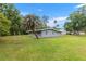 View of the backyard with a grey house, green lawn and many trees at 11065 Ne 42Nd St, Silver Springs, FL 34488