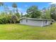Grey home's backyard with a large, green lawn, and multiple trees at 11065 Ne 42Nd St, Silver Springs, FL 34488