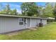 View of the grey house with utilities, an open shed and green grass at 11065 Ne 42Nd St, Silver Springs, FL 34488