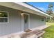 Grey home showing front door entrance with a porch and green grass at 11065 Ne 42Nd St, Silver Springs, FL 34488