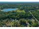 Aerial view of the property near a tranquil lake, surrounded by lush greenery and wooded areas at 16571 Se 95Th Street Rd, Ocklawaha, FL 32179