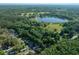 Aerial view of the property amidst a dense wooded area, near a serene lake at 16571 Se 95Th Street Rd, Ocklawaha, FL 32179