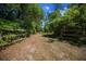 Gravel driveway leading to a gated property, bordered by lush greenery and mature trees at 16571 Se 95Th Street Rd, Ocklawaha, FL 32179