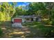Charming home with a red garage door, lush lawn and mature trees enhancing curb appeal at 16571 Se 95Th Street Rd, Ocklawaha, FL 32179