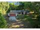 Lovely single-level home featuring a red garage door and lush green lawn with mature trees at 16571 Se 95Th Street Rd, Ocklawaha, FL 32179