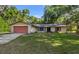 Charming single-story home with a red garage door and a well-maintained front yard surrounded by trees at 16571 Se 95Th Street Rd, Ocklawaha, FL 32179