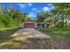 Single-story home with a red garage door complemented by the green surroundings and blue skies at 16571 Se 95Th Street Rd, Ocklawaha, FL 32179