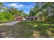 Charming single-story home with a well-maintained lawn and mature trees, featuring a red garage door at 16571 Se 95Th Street Rd, Ocklawaha, FL 32179