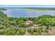 Aerial view showing home with a red roof surrounded by green trees, near a stunning blue lake at 16891 Ne 243Rd Place Rd, Fort Mc Coy, FL 32134