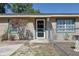 Tan home with a green trim, front door with a glass screen, a tree and a fenced in area with a concrete slab in front at 2808 Ne 24Th Ct, Ocala, FL 34470