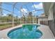 Screened-in kidney-shaped pool with blue tile border and lush landscaping, perfect for relaxation at 5331 Old Hickory Ln, Fruitland Park, FL 34731