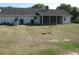 Backyard view featuring a home with white siding, screened porch, large yard and surrounding shrubbery at 5355 Sw 31St St, Ocala, FL 34474