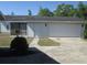 A single-car garage door and entrance with a well-maintained lawn and mature landscaping at 5355 Sw 31St St, Ocala, FL 34474
