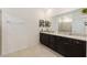 Bathroom showcases dark cabinets with granite countertop and double sinks next to glass shower at 8090 Penrose Pl, Wildwood, FL 34785