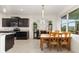 Open dining area with a wooden table set, natural light from the windows, and dark kitchen cabinetry at 8090 Penrose Pl, Wildwood, FL 34785